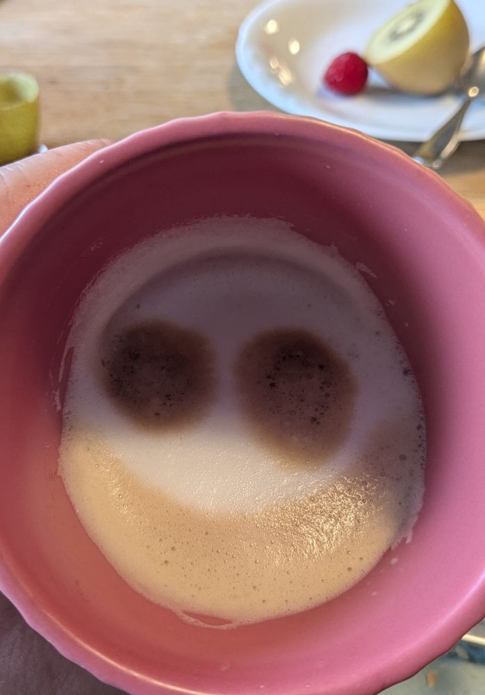 Foto in eine Tasse, Milchschaum mit Kaffee Augen und Mund. Cappuccino grinst uns an