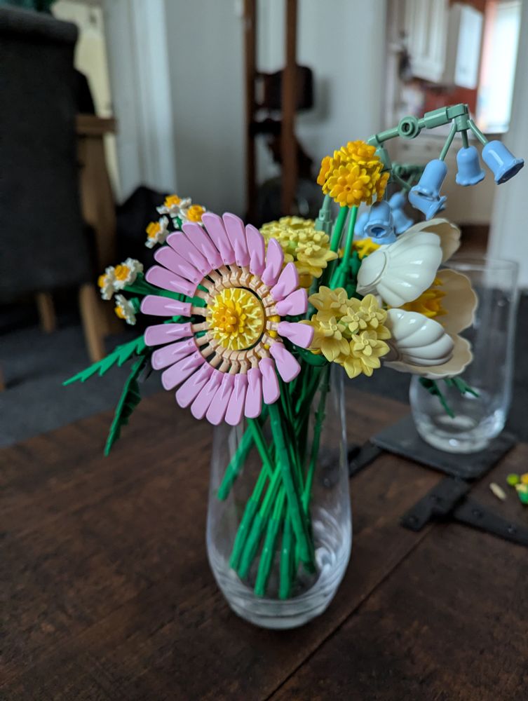 A bouquet of flowers made from Lego. The shot is focused on a Gerbera daisy, a large flower with pink pettles.