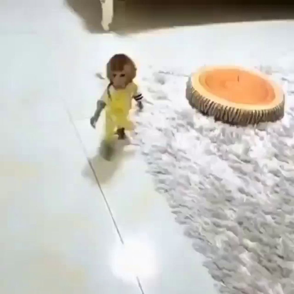 a small monkey in yellow overalls is walking on a white tiled floor