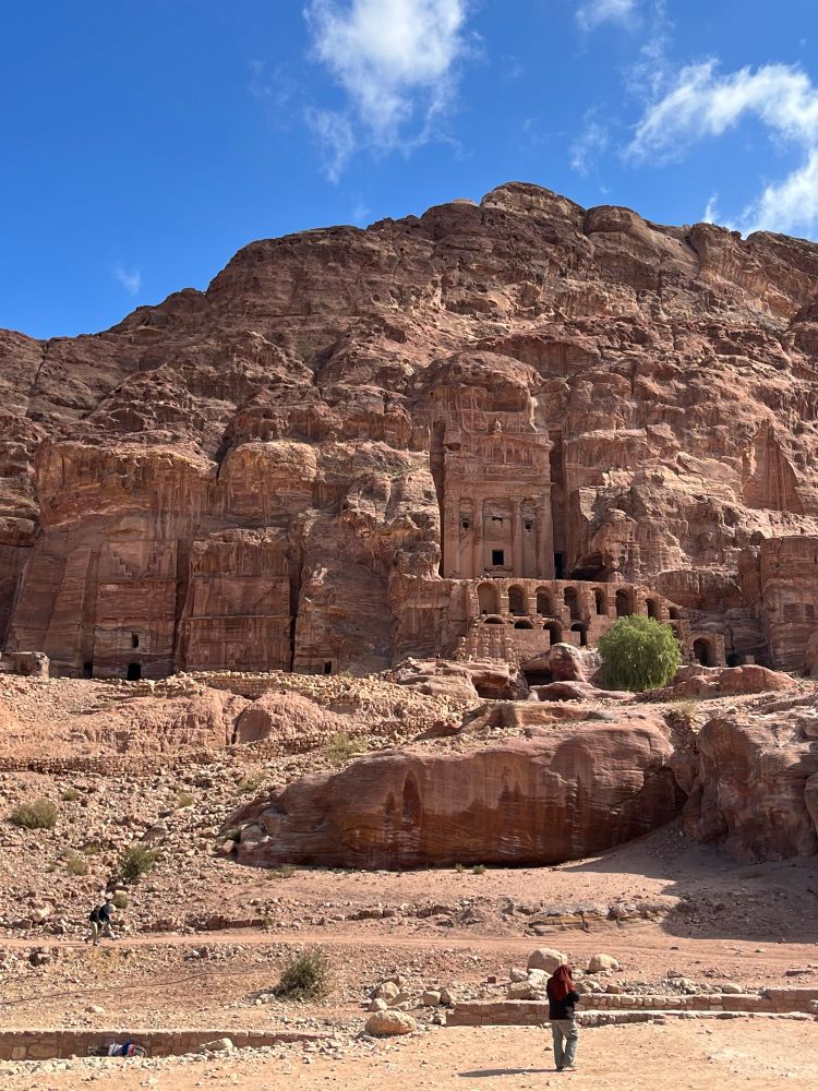 Several arches carved into the pink rock, over which is another huge facade tomb structure. 