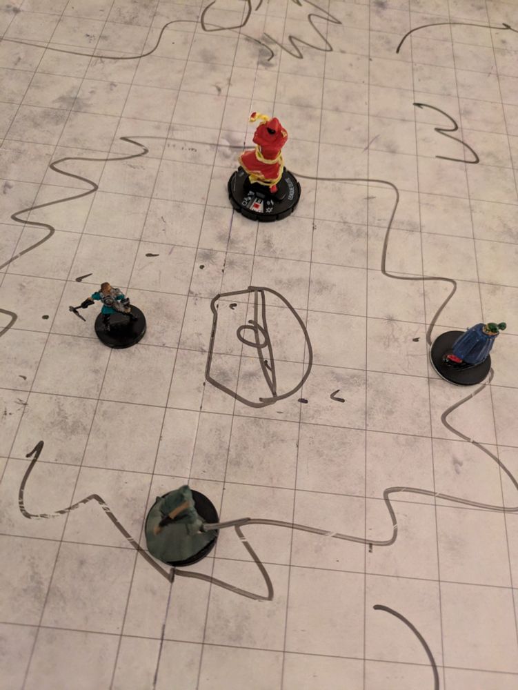 Miniature D&D figurines on a grid map surrounding s drawing of a large treasure chest.
