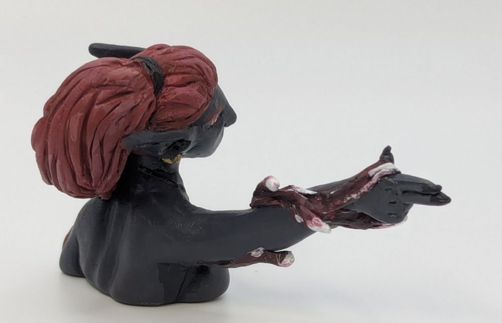 A bust of a humanoid character with long red hair, pointed ears, and dark grey skin. She is pointing a finger gun and aiming down sights. Blood magic spirals around her arm.