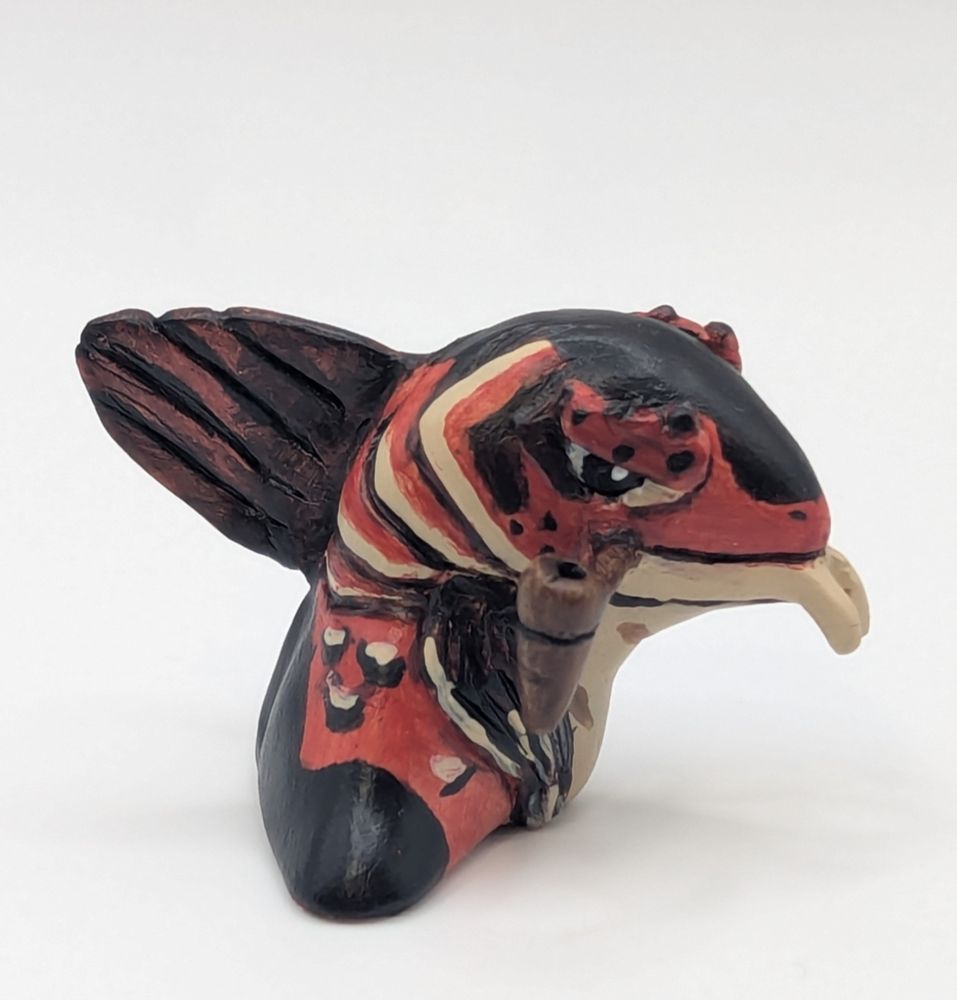 A polymer clay statute of a anthropomorphic fish person. His colours are primary a blue black, brighter red brown, and tan. He has a cute little pipe.