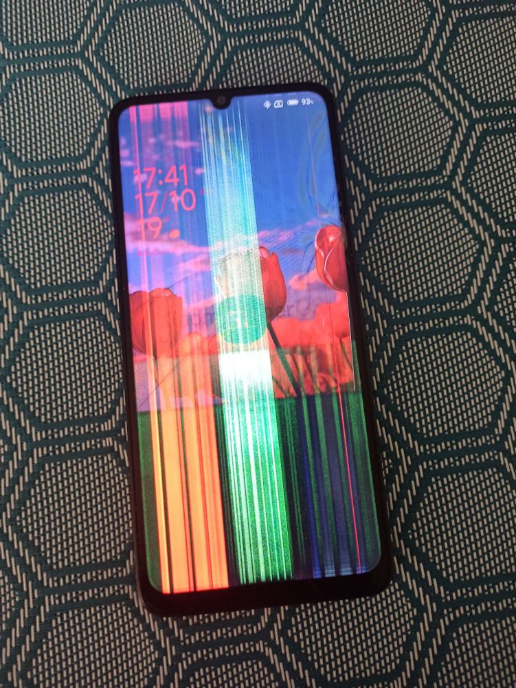 Téléphone Xiaomi avec un écran défectueux posé sur une table.