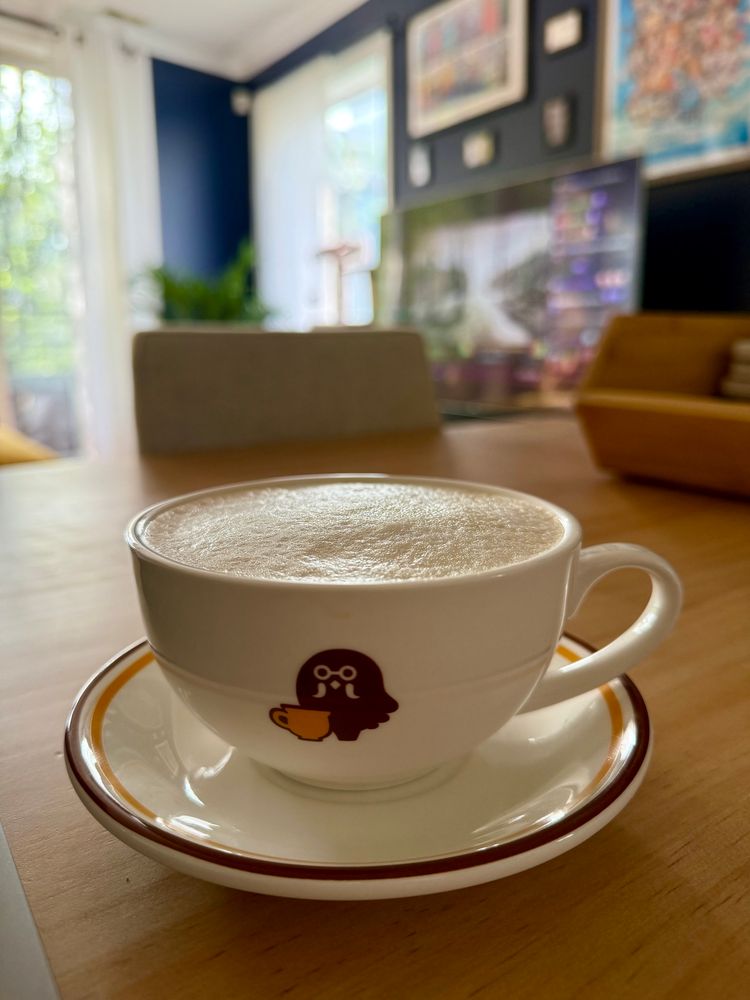 Cafe au lait in a Brewster mug atop a table. Games Done Quick is visible on the TV in the background. 