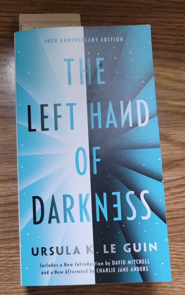 Photo of book Left Hand of Darkness by Ursula Le Guin on a faux wood table. 