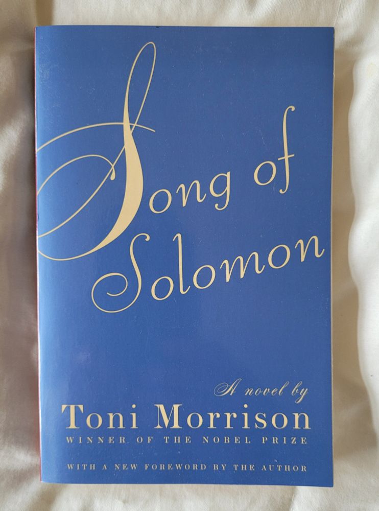 Photo of book Song of Solomon by Toni Morrison on an off-white comforter. 