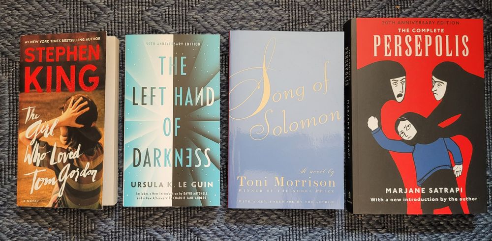 Photo of the four books listed in the post side by side on a dark blue woven rug.