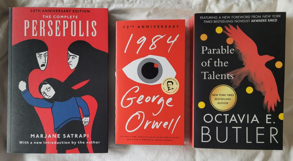 Photo of the three books listed in post side by side on a white comforter. 