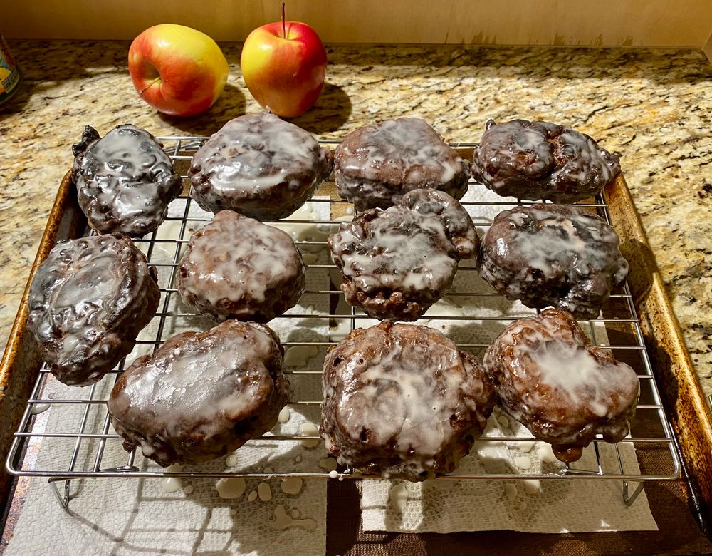 A metal drying rack covered in 11 glazed apple fritters
