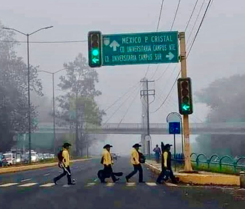 A photo of a band of musicians crossing the road in a style that evokes The Beatles' famous Abbey Road album cover. 