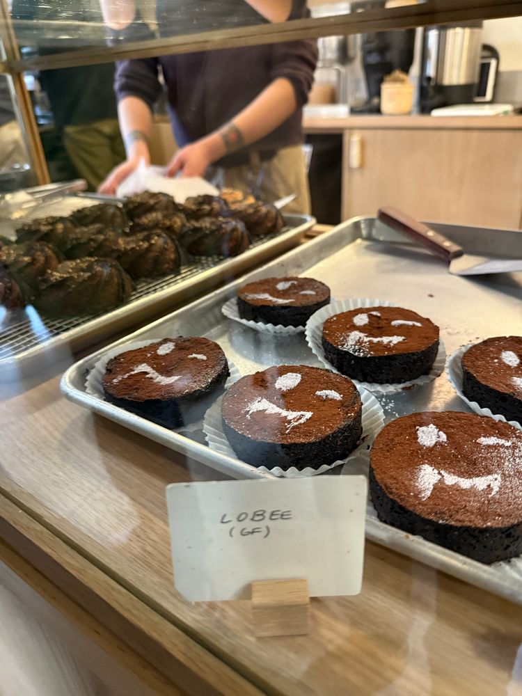 A collection of brownie discs with vampire faces dusted on them with powdered sugar and sesame canneles in the background 