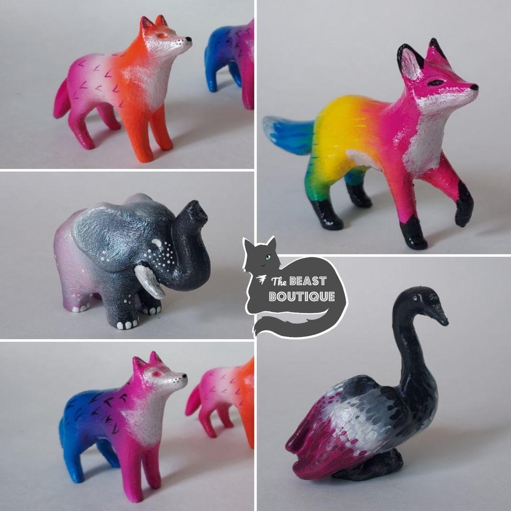 A collage of five figurines painted in colors to resemble LGBT pride flags. clockwise from the top right: A pan flag fox, and ace flag goose, a bi flag wolf, an ace flag elephant, and a lesbian flag wolf.

The image is watermarked with a logo of a one eyed grey cat and the words "The Beast Boutique" 