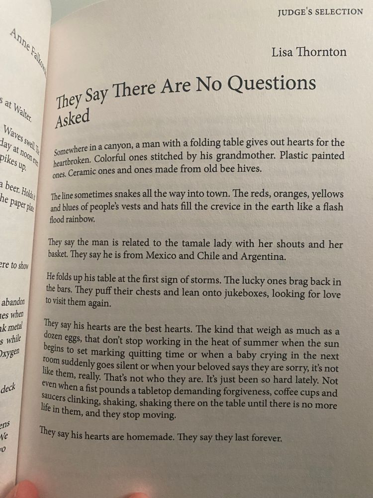A picture of my story inside the book which is titled “They Say There Are No Questions Asked” and the full text: Somewhere in a canyon, a man with a folding table gives out hearts for the heartbroken. Colorful ones stitched by his grandmother. Plastic painted ones. Ceramic ones and ones made from old bee hives. The line of people sometimes snakes all the way into town. The reds, oranges, yellows, and blues of people’s vests and hats fill the crevice in the earth like a flash flood rainbow. They say the man is related to the tamale lady with her shouts and her basket. They say he is from Mexico and Chile and Argentina. He folds up his table at the first sign of storms. The lucky ones brag back in the bars. They puff their chests and lean onto jukeboxes, looking for love to find them again. They say his hearts are the best hearts. The kind that weigh as much as a dozen eggs, that don’t stop working in the heat of summer when the sun begins to set marking quitting time or when a baby crying in the next room suddenly goes silent or when your beloved says they are sorry, it’s not like them, really. That’s not who they are. It’s just been so hard lately. Not even when a fist pounds a tabletop demanding forgiveness, coffee cups and saucers clinking, shaking, shaking there on the table until there is no more life in them, and they stop moving. They say his hearts are homemade. They say they last forever.