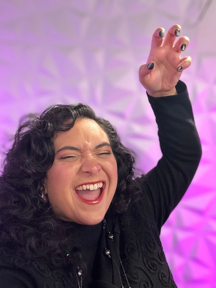 Natalie raises a hand with her fingers crooked in a “paws up” gesture popular among Lady Gaga’s Little Monsters