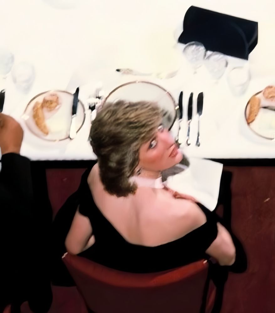 Princess Diana looking up from a dining room table