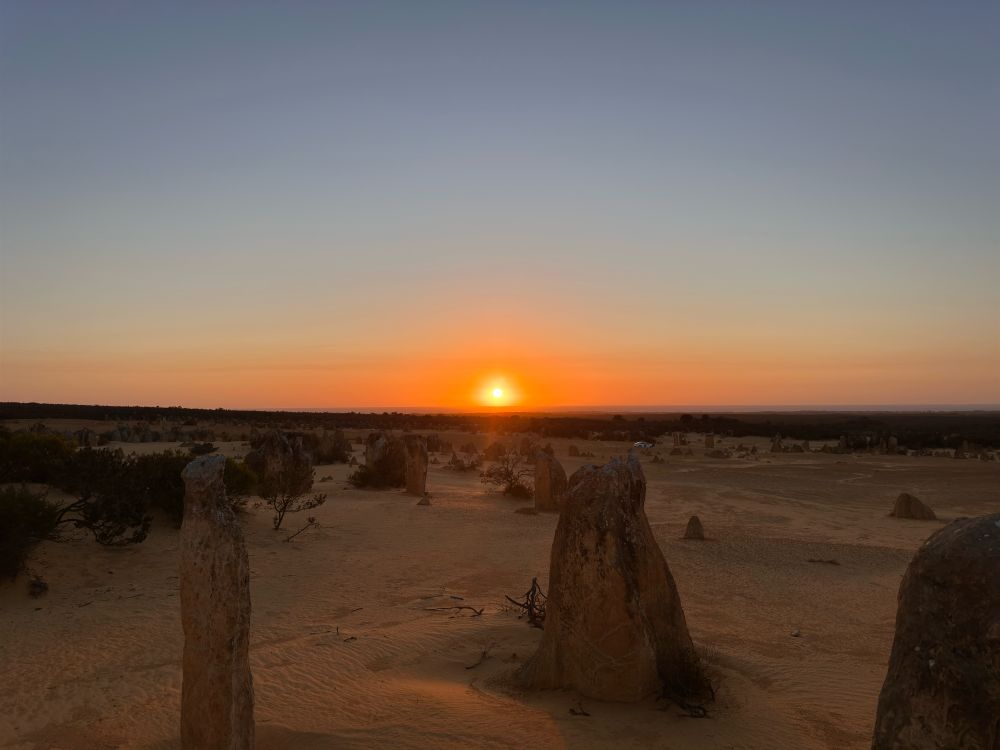 Rock pinnacles standing on sand in front of sunset