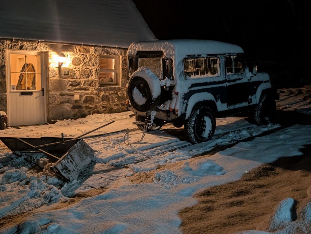A nighttime scene of a Defender 90 outside a stone building with a towplough of my own design and manufacture behind it. 