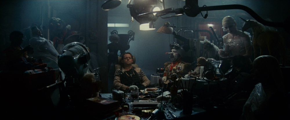A gathering of individuals seated in a deliberate arrangement around a table, bathed in subdued lighting.