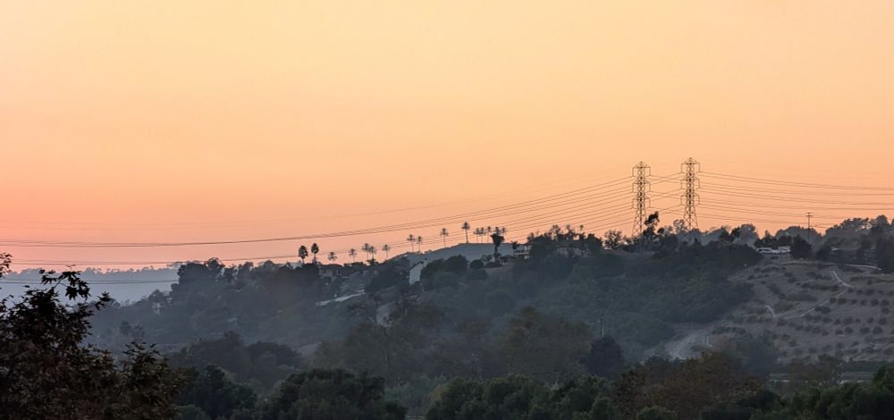 a californian sunset with a pair of power lines on the horizon.