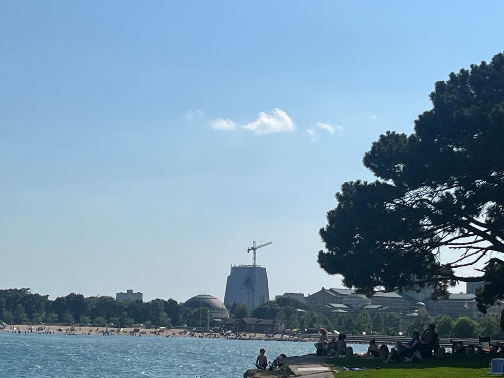 The Obama center rising from Promontory Point, blue skies, with the lake and beachfront in the foreground