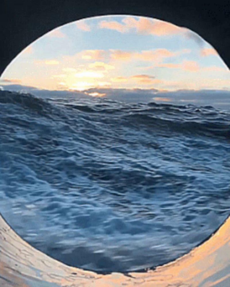 a sunset over the ocean is reflected in a round window