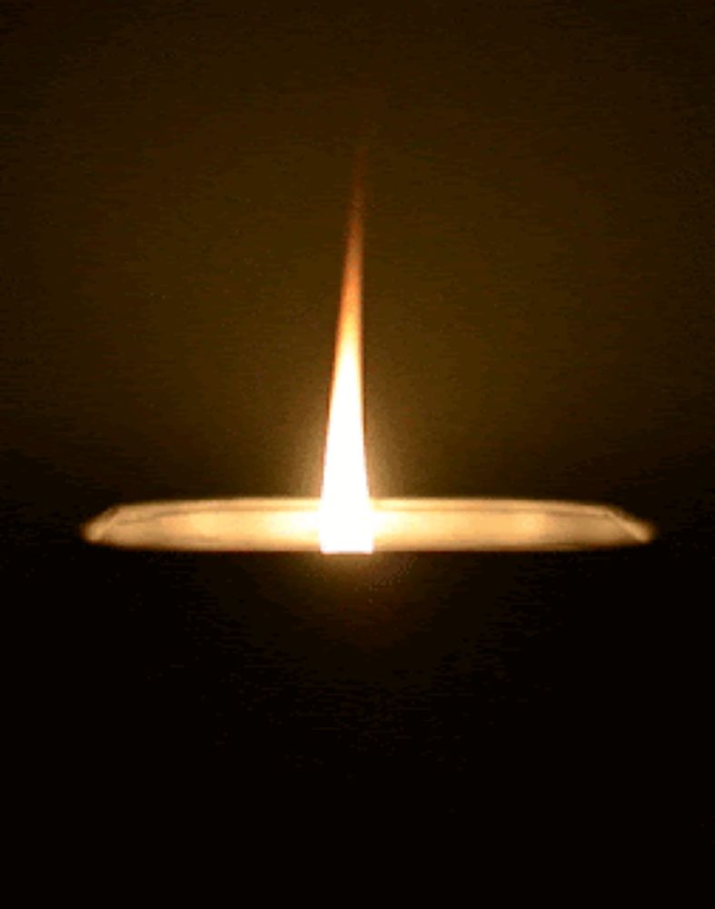 a candle is lit up in the dark and has a very long flame