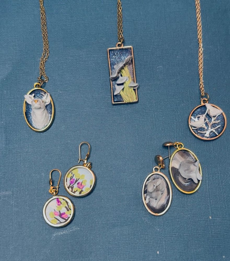 The whole group of a floral earring set, the magic rabbit earrings, the birds in tree pendent, a silver stag pendant, and a green and blue mushroom pendant