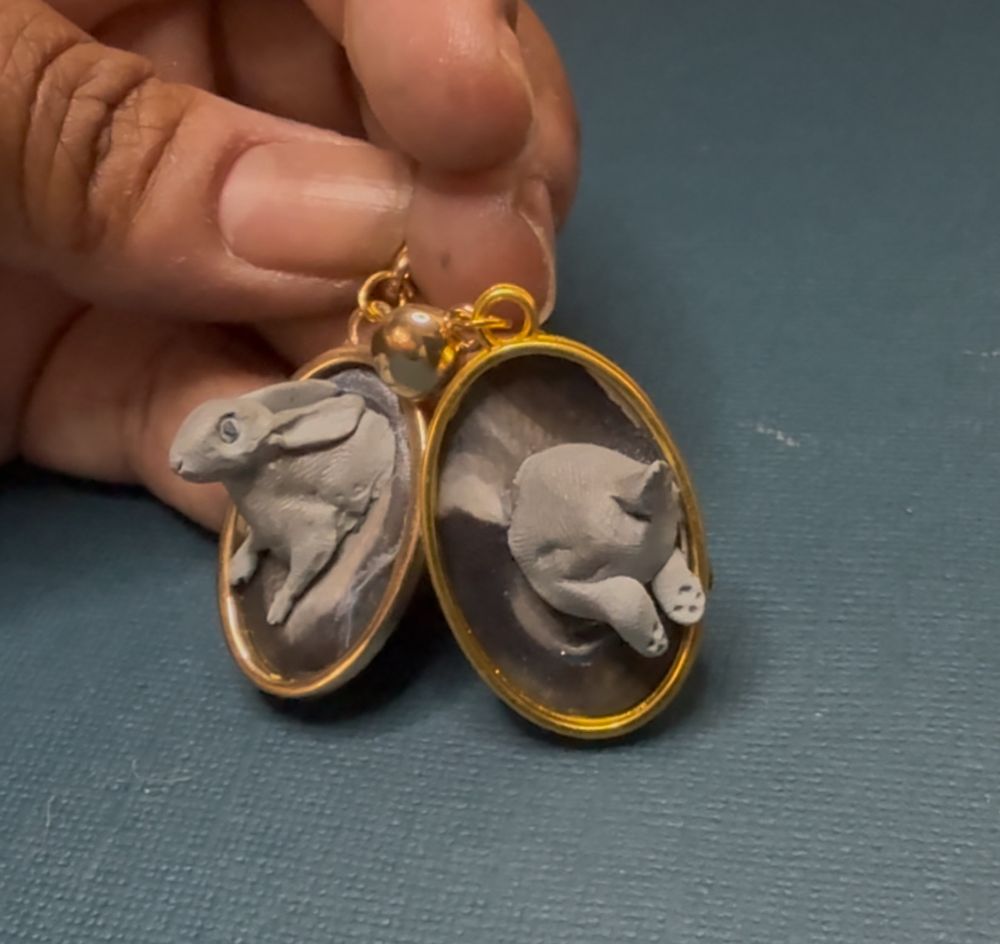 Magic rabbit earrings, clay in gold bezels. Fluffy butt disappears into the earring on the right and the head and chest leap out of the one on the left. 