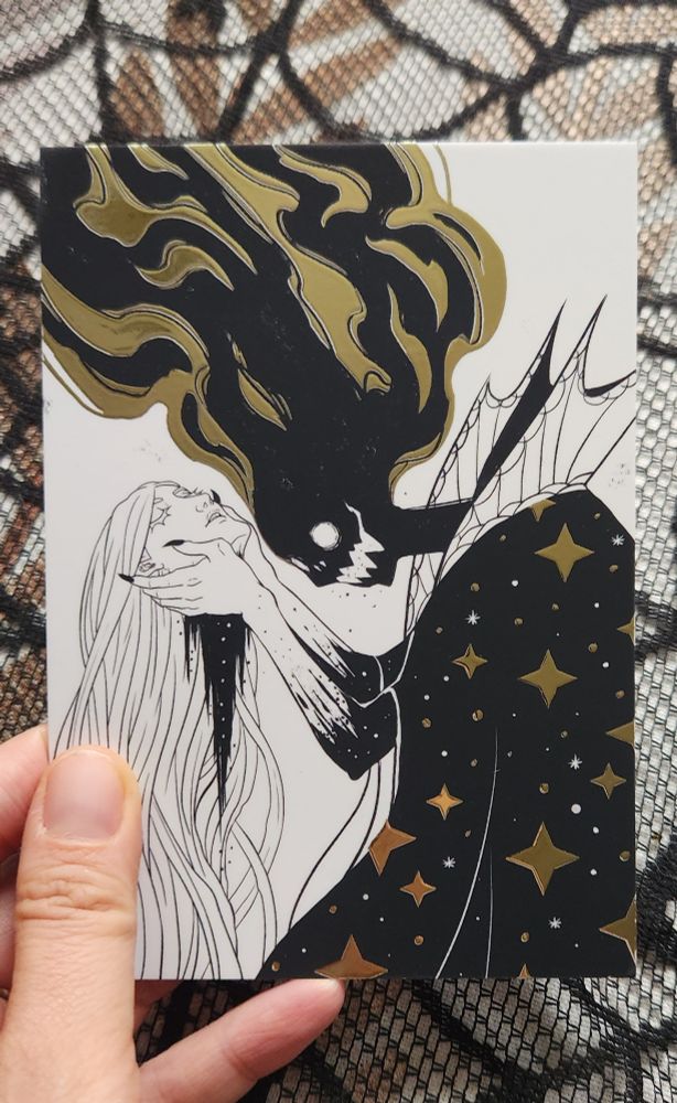 Black white and gold illustration of a demonic figure holding a beautiful woman's head with long hair