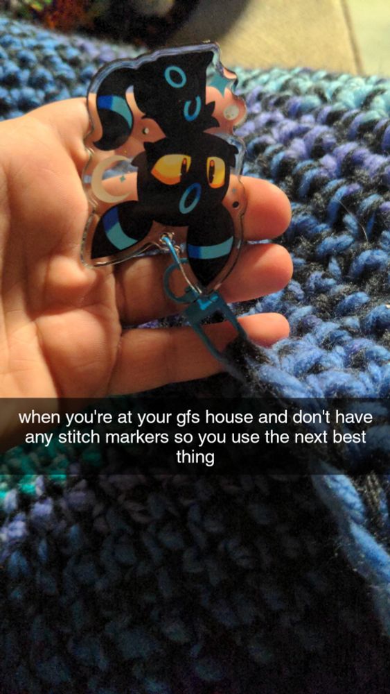 a work in progress crochet sweater with a shiny Umbreon clip used as a stitch marker. 
the text is the same as the caption 