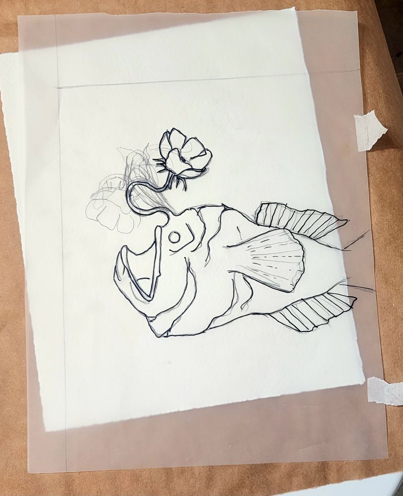 Drawing of angler fish with flower on tracing paper placed over white watercolor paper. 
