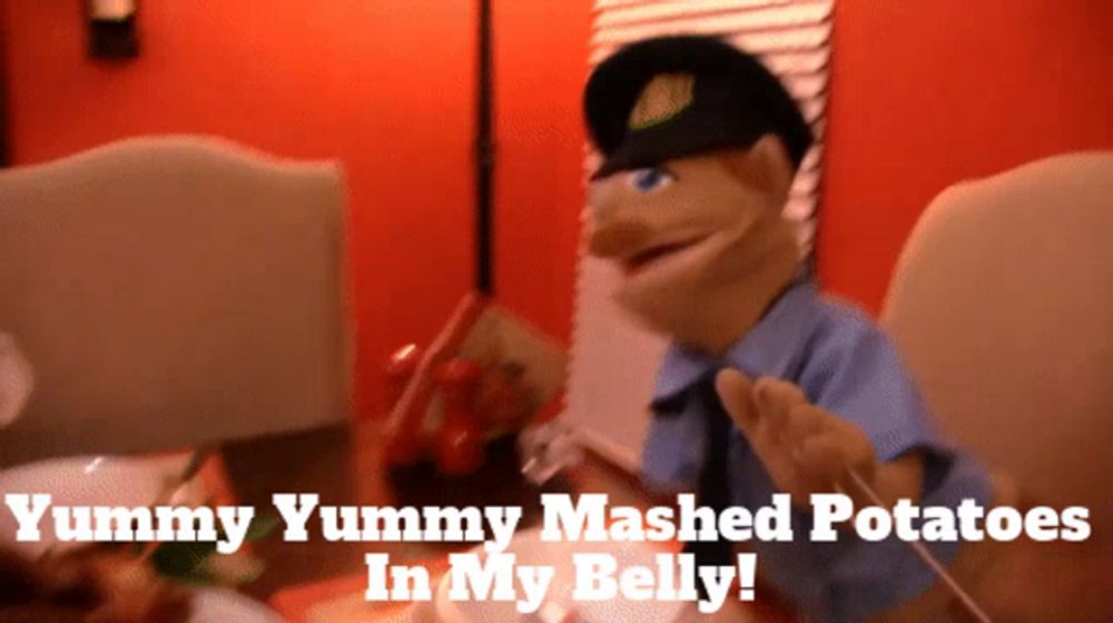 a puppet is sitting at a table with mashed potatoes in his belly