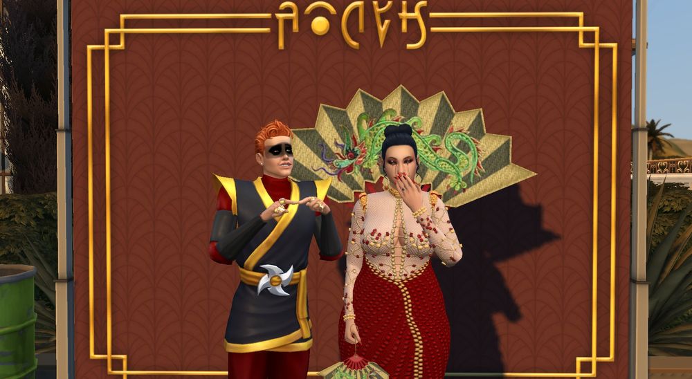 dax in a ninja costume, standing next to gia with a dorky look on his face and index fingers pointed into each other. gia in her bob mackie inspired costume, with a playful hand over her mouth.