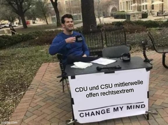 Mann an Tisch, mit Schild mit Aufschrift "CDU und CSU mittlerweile offen rechtsextrem. Change my mind."