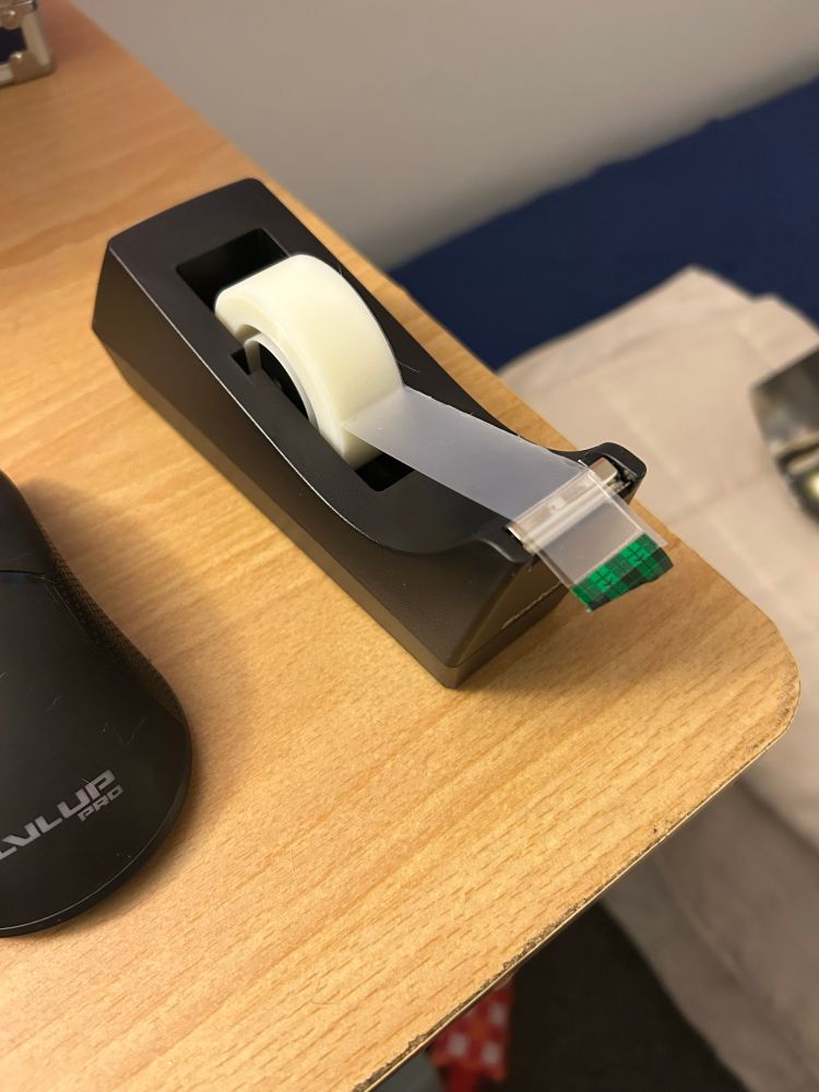 A desktop tape dispenser sitting on a wooden desk