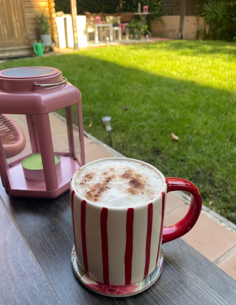 Taza de café con espumita en el jardín al fresco