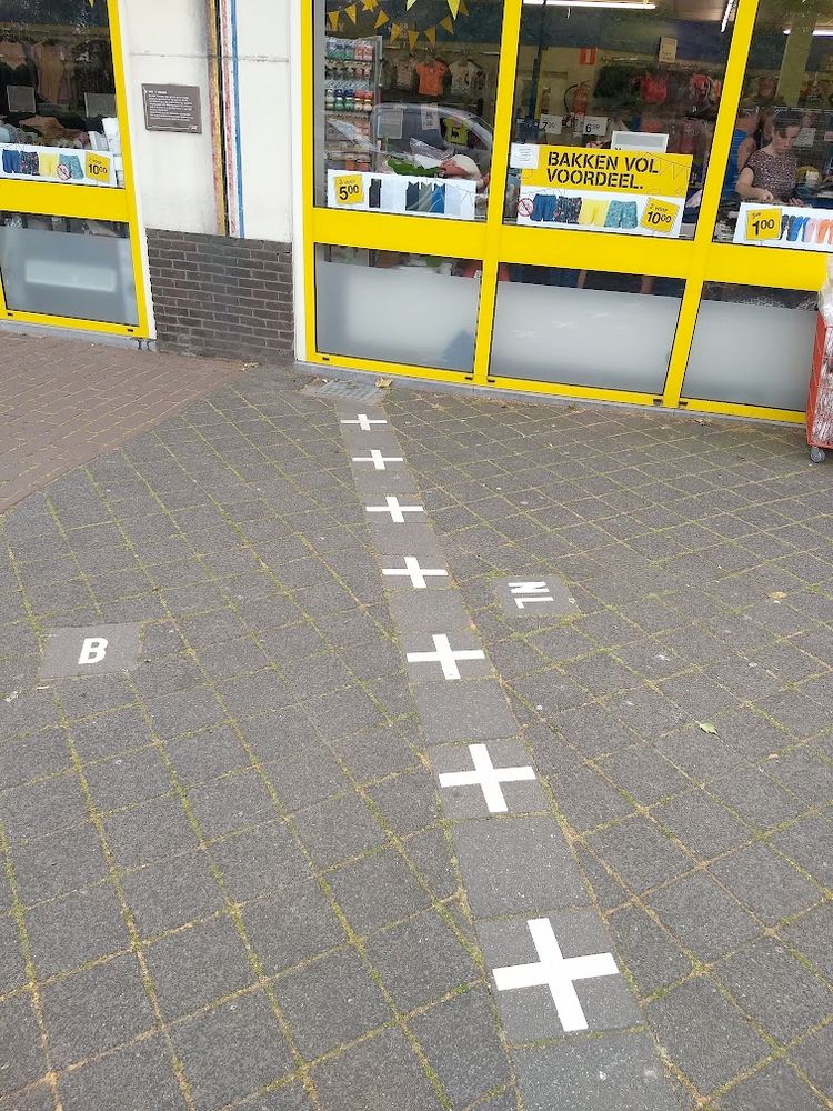 The border line between Belgium and the Netherlands in Baarle, as indicated by symbols and the letters 'B' and 'NL' formed from tiles in the street. The border goes right through a clothing shop, dividing the building between both countries.