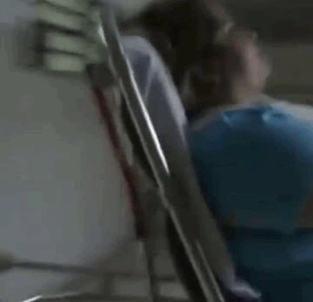 a woman in a blue shirt is laying in an ambulance while a man stands behind her .