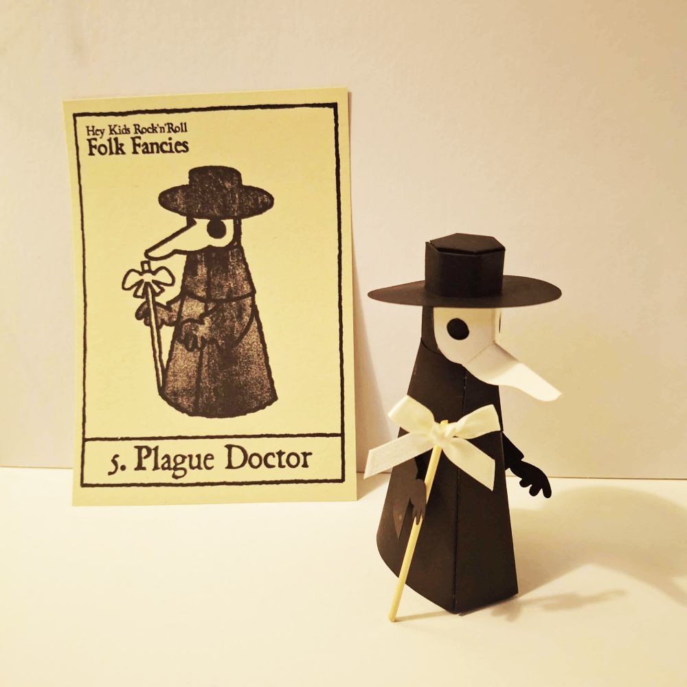 A paper model of a Plague Doctor, all black except for a white mask with a long snout. He holds a staff (which is a cocktail stick with a white ribbon attached)