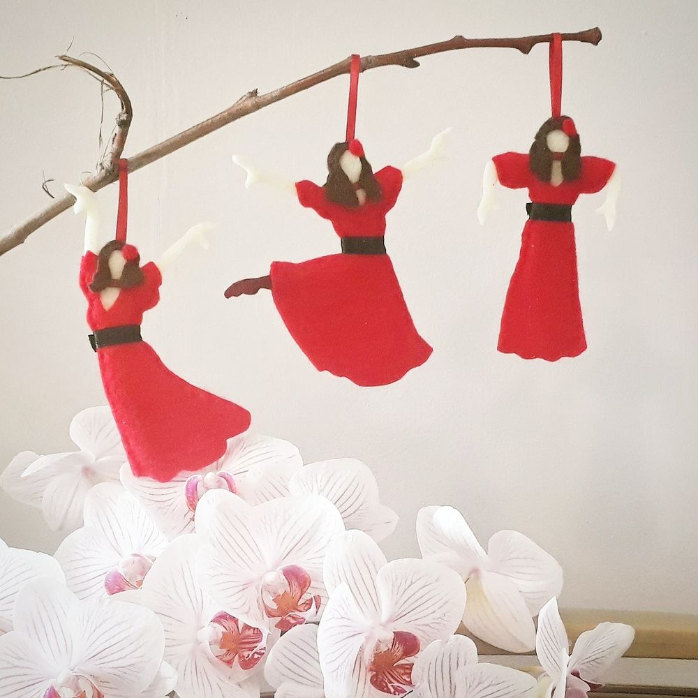 handmade felt decorations hanging on an orchid. They depict Kate Bush in her Wuthering Heights red dress.
