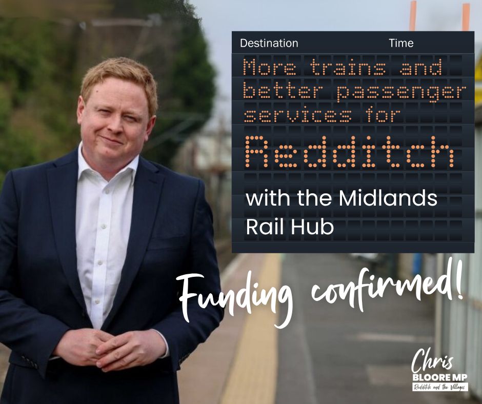 Chris stands on Redditch platform next to a board celebrating the announcement