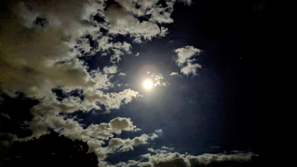 Moon shines it's light on clouds in a darkened Autumn night sky.