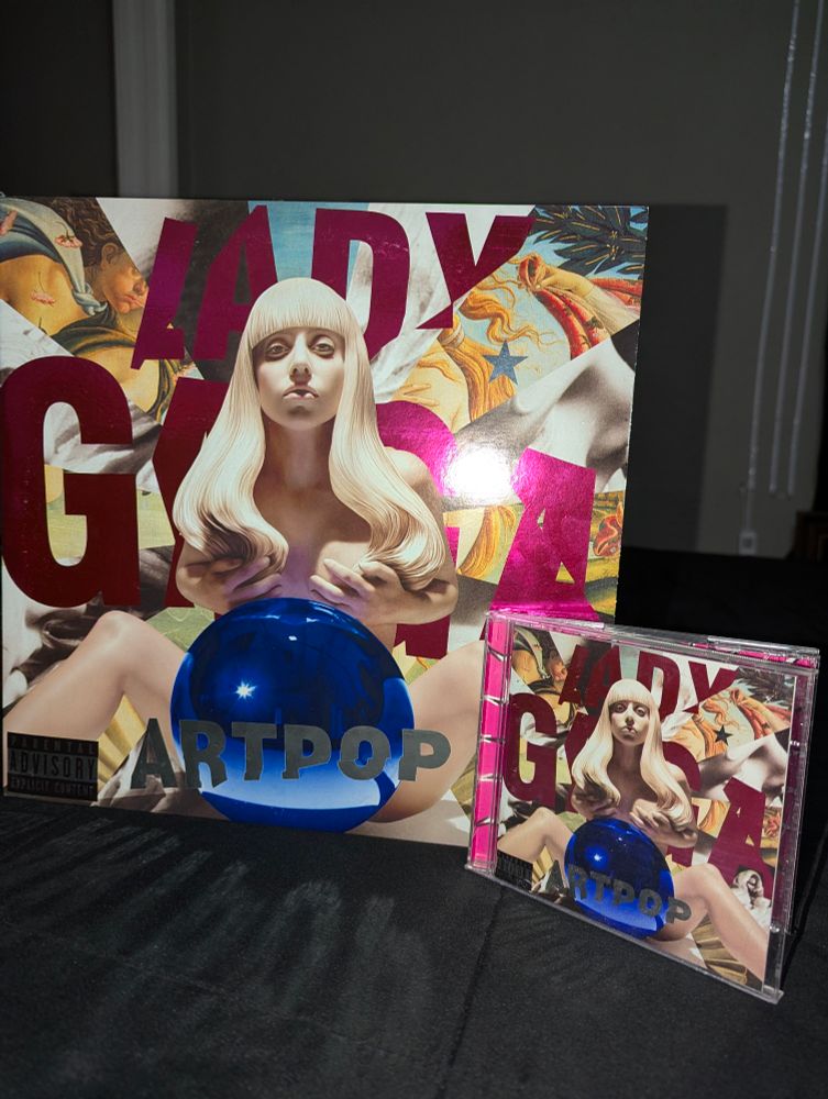 photograph of a vinyl and CD of Lady Gaga's 2013 album, ARTPOP, featuring the aluminium foil covers on both, which in the right light makes the text and Parental Advisory sticker shine (bc it's aluminium).