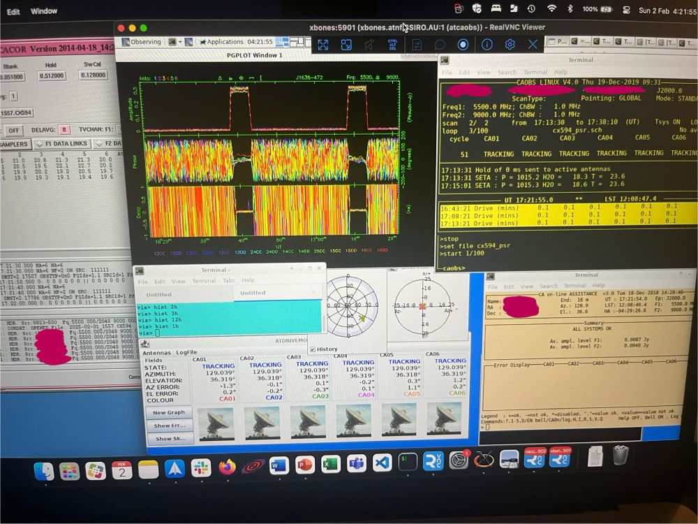 Photograph of a computer screen with many windows open, some of which show colourful squiggly lines indicating how well a radio telescope is performing.