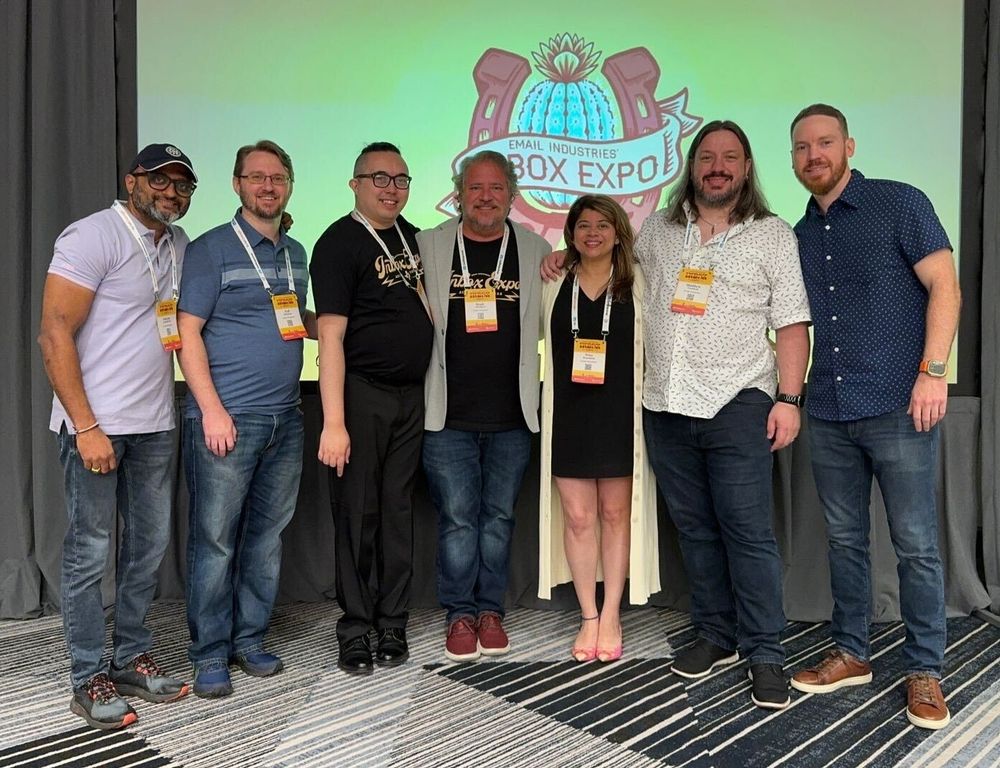 Seven team members from Email Industries standing in front of the Inbox Expo projection screen - Austin, TX