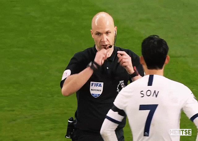 a referee wearing a fifa referee shirt talks to a soccer player wearing a number 7 jersey