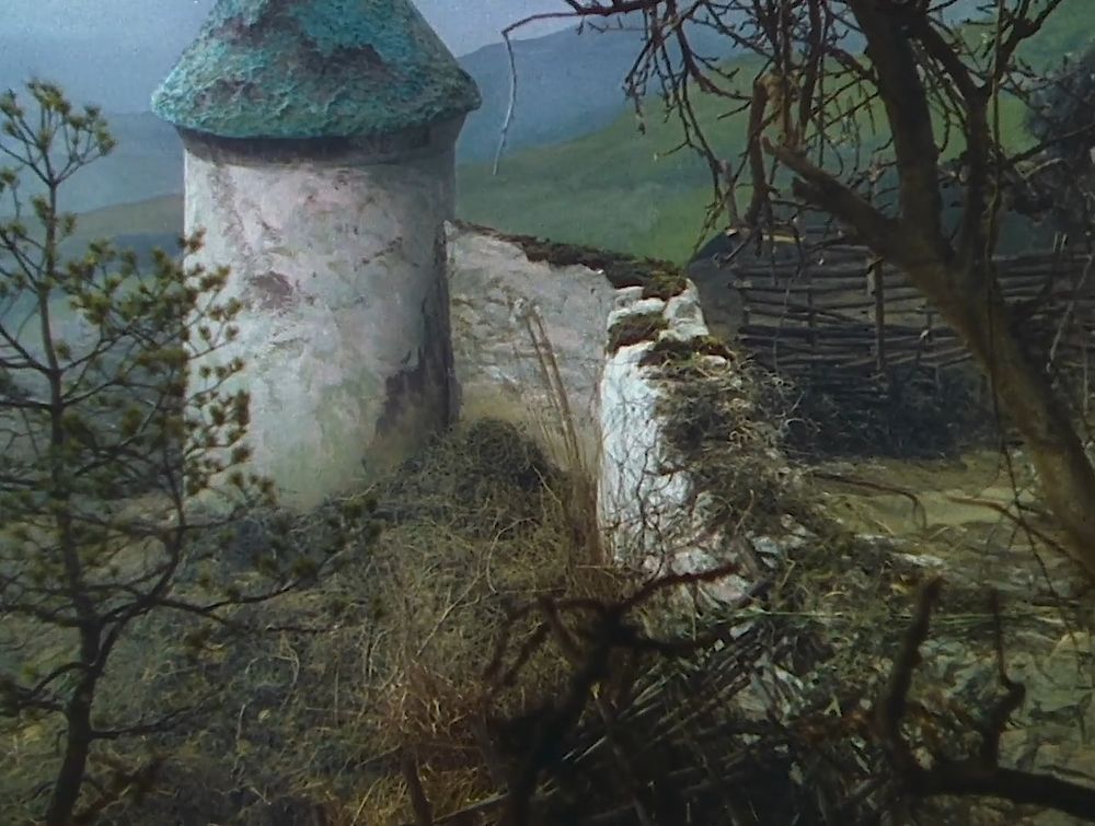 A look through a thicket towards a ruined tower.