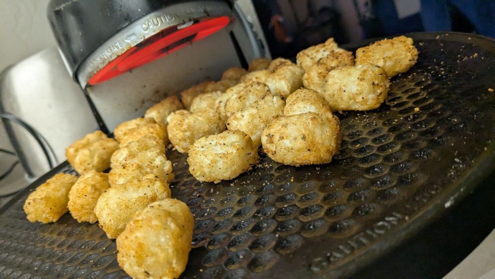 seasoned tater tots roasting on an open rotating oven