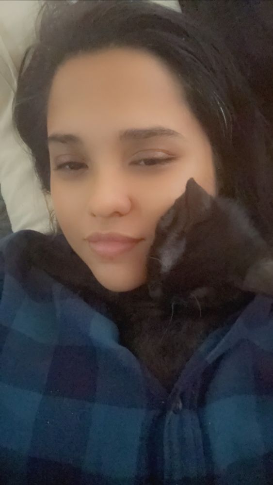 Picture of the user with a small black kitten snuggled into their neck while inside their button up shirt